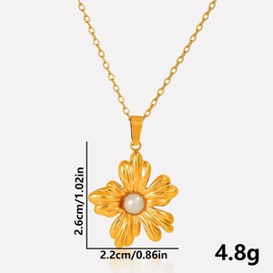 Detail shot of golden flower pendant with pearl, measuring 2.6cm by 2.2cm on a thin chain