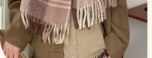 Detailed texture of thick plaid tassel scarf in pink and brown with wool-like finish