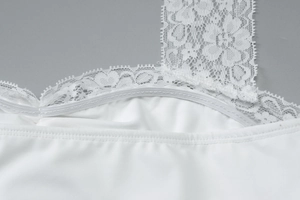 Dettaglio del bordo in pizzo bianco e della spallina elastica sul vestito attillato