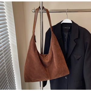 Detail of caramel brown suede hobo bag featuring decorative stitching and leather strap