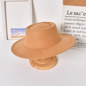 Detail view of a camel wide-brim wool felt fedora hat on a wooden stand in a studio setting