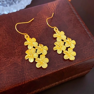 Retro 18K gold flower drop earrings with matte finish on elegant leather background