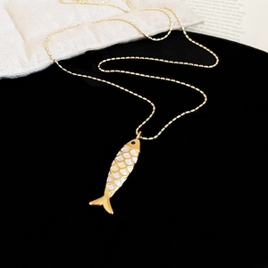 Detail of a golden fish pendant with white enamel inlay and a delicate beaded chain