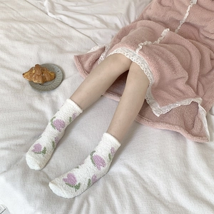 Detailed texture of thick white coral fleece socks featuring purple floral patterns