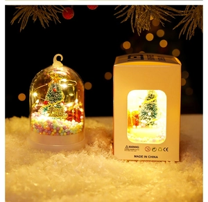 Detail of a Christmas glowing glass dome with mini tree, gifts and LED lights in its gift box