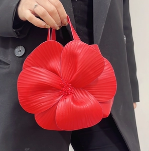 Macro shot of 3D petal texture and beaded center on a red floral leather tote bag