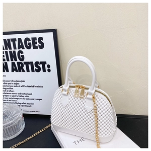 Detail of white PVC shell bag featuring grainy texture and gold chain strap accents