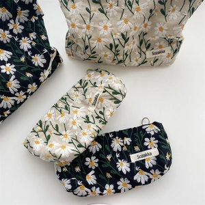 Detailed embroidery of white daisies on navy and beige canvas cosmetic bags