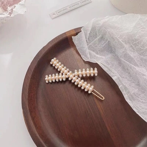 Detailed close-up of pearl and rhinestone hair clips on a minimalist wooden tray