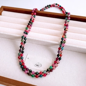 Detail of colorful round agate bead necklace on a white fabric jewelry display tray