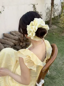 Detail of a light yellow lace scrunchie with intricate floral eyelet embroidery texture