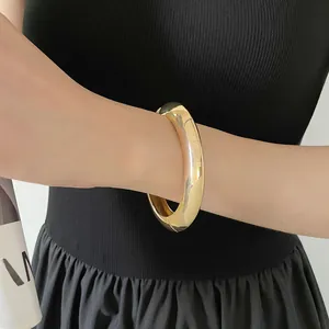 Vue détaillée d'un bracelet large en métal doré poli avec une finition miroir minimaliste