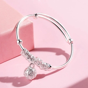 Dettaglio del bracciale in argento con perle intagliate e ciondolo a sfera cava