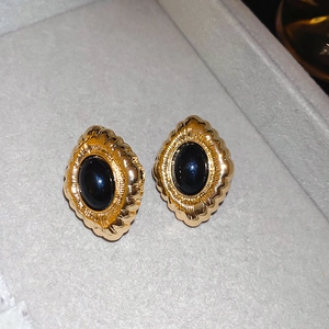 Detail of vintage gold flower earrings with black oval gemstone on gray velvet