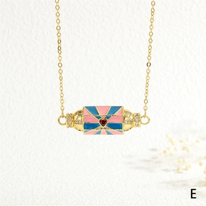 Close-up of golden rectangular enamel pendant with pink and blue sunburst pattern