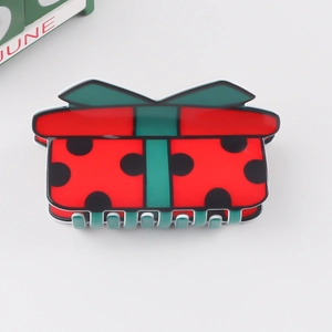 Détail d'une pince à cheveux en forme de cadeau de Noël rouge et vert avec nœud élégant