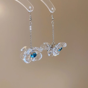 Detailed close-up of acrylic flower earrings with blue crystal and silver hooks