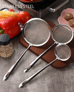 Three sizes of stainless steel kitchen mesh strainers on a professional kitchen counter