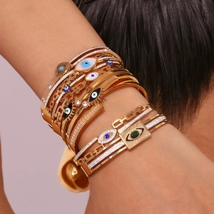 Close-up of layered gold evil eye bracelets with zircon and enamel on female wrist