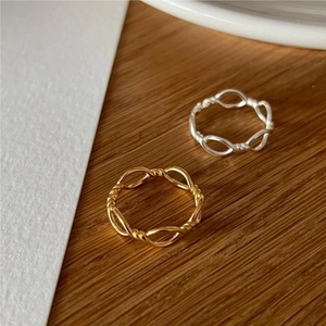 Detail of twisted 925 silver rings in gold and silver finish on a wooden surface