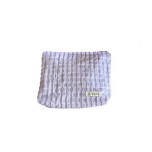 Purple and white checkered seersucker makeup bag with a stylish zipper and woven label