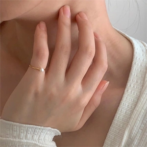 Detail of elegant gold band ring with a round white pearl on a model's finger