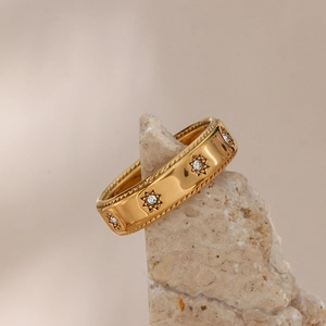Vue macro d'une bague en acier plaqué or avec gravure d'étoiles et pierres claires