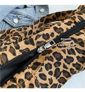 Detailed close-up of smooth silver metal zipper on leopard print canvas tote bag