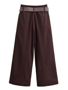 Dettaglio di pantaloni marroni a gamba larga con un'elegante cintura grigia a contrasto