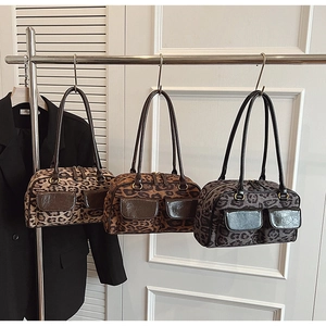 Detailed shot of three leopard print boston bags with dual front pockets and long straps