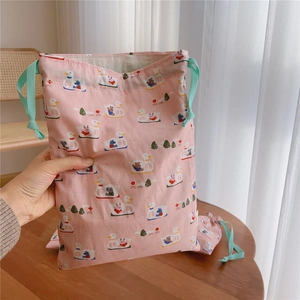 Detailed view of pink drawstring cotton bag with duck and boat print and green strings