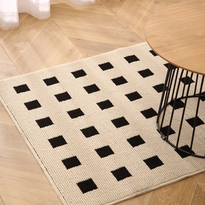 Modern black and white checkered entryway rug on wooden floor for a minimalist home decor