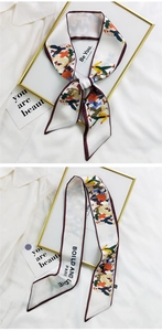Close-up of narrow silk twilly scarf with colorful illustration and burgundy border