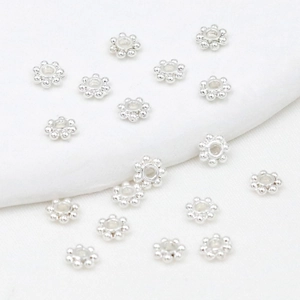 Macro shot of silver flower gear spacers for DIY jewelry making with metallic finish