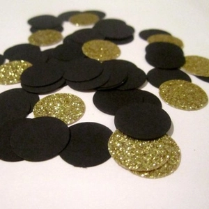 Glittery gold and black graduation party confetti scattered on a clean white background