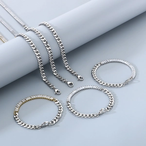 Detailed view of silver Cuban link chains and zircon bracelets on a gray pedestal