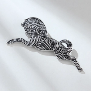 Close-up of vintage silver running horse brooch with detailed dotted texture and metallic finish