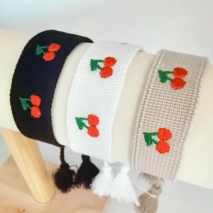 Detail view of colorful embroidered cherry wristbands with decorative tassels