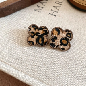 Macro detail of clover earrings with leopard print fur texture and brown metal edges