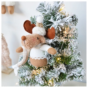 Plush Christmas reindeer ornament with scarf hanging on a snow-covered tree branch