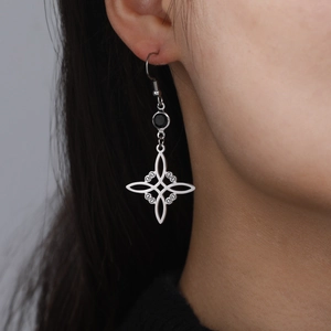 Detail of stainless steel hollow witch knot earring with black bead on model's ear