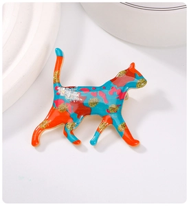 Detailed close-up of a colorful enamel cat brooch with gold glitter and metal finish