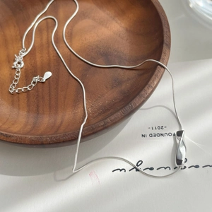 Detail of silver S925 sterling silver snake chain with irregular pendant on wooden disk