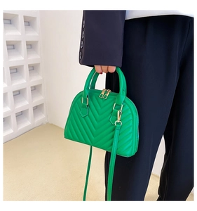 Detailed view of green shell bag with V-quilted leather and golden hardware on model