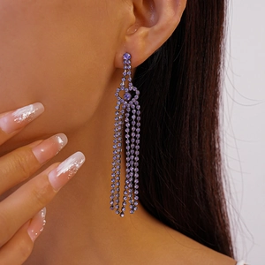 Detail of elegant silver drop earrings featuring long purple rhinestone tassels on model