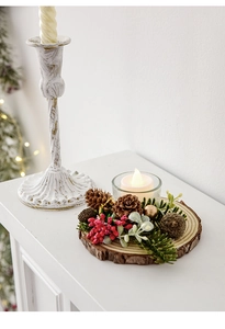 Macro detail of Christmas candle holder with natural wood base, pine cones and red berries