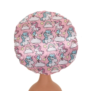 Close-up of pink satin bonnet with unicorn prints and elastic band on a mannequin