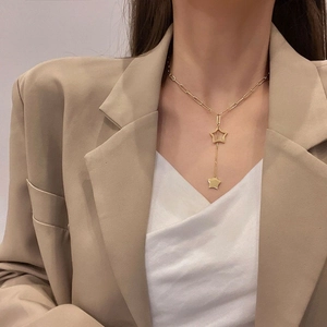 Detail view of gold Y-shaped necklace with cutout star pendants on paperclip chain