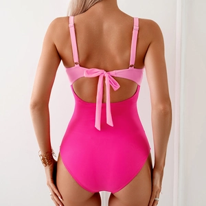 Detail of the back cutout on a pink colorblock swimsuit with a decorative ribbon bow
