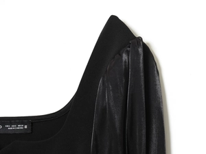 Dettaglio di top nero da donna con bottoni e contrasto tra maglia e tessuto satinato